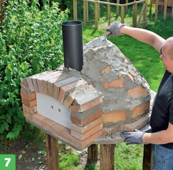 Kupolens övre del på murad pizzaugn Kupolens övre del på murad pizzaugn görs klar med ett tjockt lager bruk